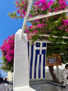 a white and blue building with flowers growing on it's roof next to a tree