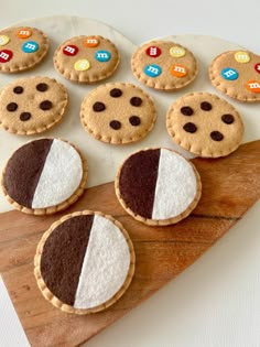 some cookies are sitting on top of a wooden cutting board and have different colored buttons