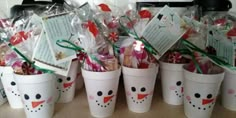 several cups with candy in them are decorated like snowmen and have tags on them