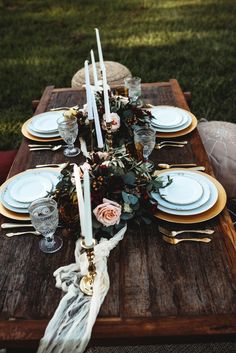 a wooden table topped with plates and candles