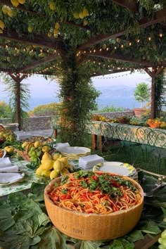 a large bowl filled with lots of food on top of a table covered in greenery