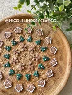 cookies are arranged in the shape of houses and trees on a wooden platter with greenery