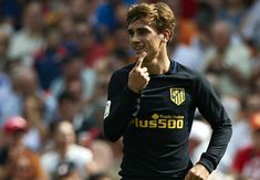 a man in black shirt pointing to the side while people watch from stands behind him