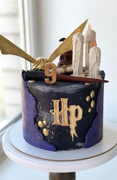 a harry potter themed birthday cake with candles and wands on the top, sitting on a table