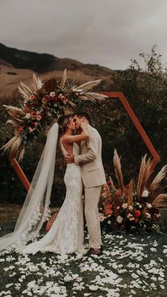 a bride and groom standing in front of a floral arch