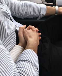 two people holding hands while sitting in a car