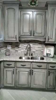 a kitchen with gray cabinets and marble counter tops