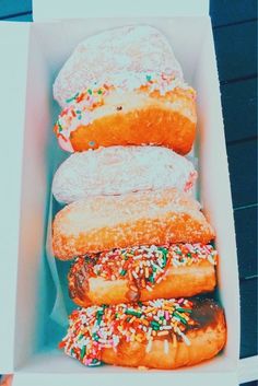 four donuts in a box with sprinkles on them