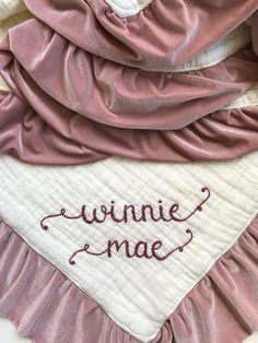 the name winnie mae is embroidered on top of a pink and white blanket with ruffled edges