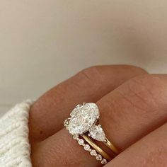 a woman's hand holding a ring with two pear shaped diamonds on top of it