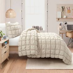 a bedroom with a bed, desk and computer on the floor in front of a window