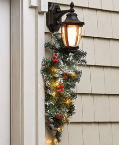 a light on the side of a house decorated for christmas with pine cones and lights