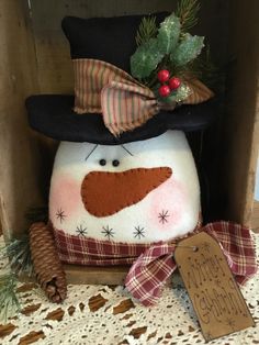 a snowman with a hat and scarf on it's head sitting next to pine cones