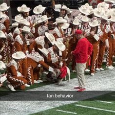 a group of men in red shirts and white hats standing on top of a field