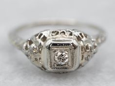 What a precious ring that dates to the early 1920s! Beautiful scrolling filigree work cascades from the center diamond down the shoulders, bringing elegance even to the back of the ring. We've set this mounting with a beautiful twinkling diamond. The smooth, polished illusion setting gives the diamond a pretty frame as well as added security. This ring would make a wonderful engagement or promise ring and would pair with a variety of wedding band styles. Metal: 14K White GoldGem: Diamond .04 Car Art Deco Diamond Ring Engagement, Art Deco Diamond Ring, Deco Diamond Ring, Filigree Ring Gold, Diamond Ring Engagement, Wedding Band Styles, Engagement Ring Art Deco, Precious Rings, Art Deco Diamond Rings