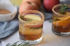 an apple cider cocktail with rosemary garnish on the rim