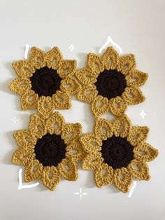 four crocheted sunflowers on a white surface