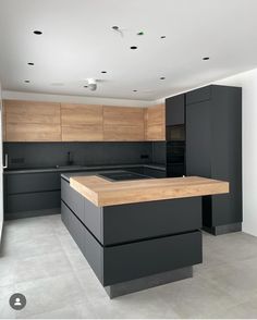 a modern kitchen with black cabinets and wooden counter tops, along with an island in the middle