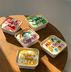 four birthday cake shaped like rainbows and the words happy new year are in small trays on a wooden table