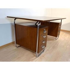 two wooden desks with metal handles in an empty room, one has a drawer on the side