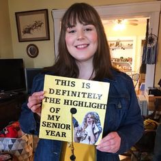 a girl holding up a sign that says, this is definitely the highlight of my senior year