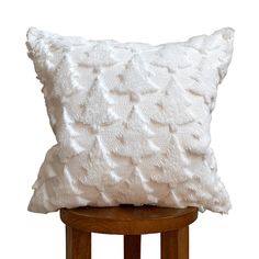 a white pillow sitting on top of a wooden stool