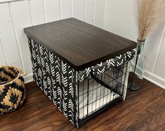 a dog crate sitting on top of a hard wood floor next to a vase with dry grass in it