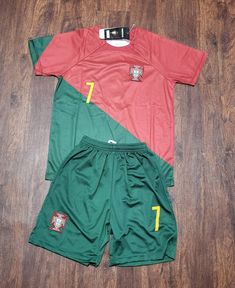 two soccer uniforms sitting on top of a wooden floor next to each other, one red and one green