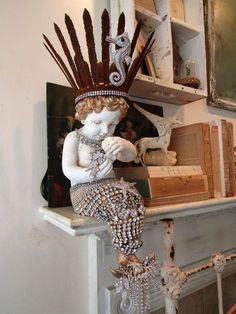 a statue of a woman with feathers on her head sitting on top of a shelf