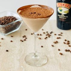 a martini glass filled with chocolate and coffee beans next to a bottle of bailey's