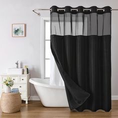 a bath tub sitting next to a window covered in black sheer curtaines and a white sink