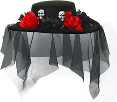 a black hat with red roses and skulls on the top is sitting on a mesh tablecloth