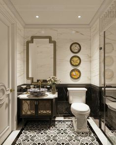 a white toilet sitting next to a sink in a bathroom under two clocks on the wall