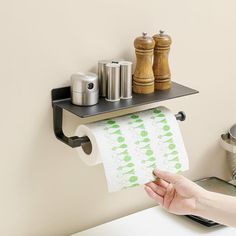 a person holding a roll of toilet paper in front of a wall mounted shelf above a sink