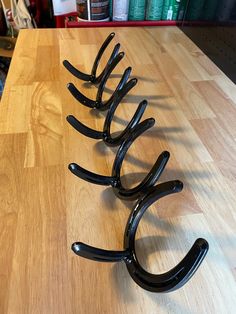 four black metal hooks on a wooden table