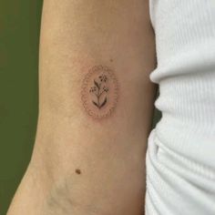 a woman's arm with a small flower tattoo on the back of her left arm