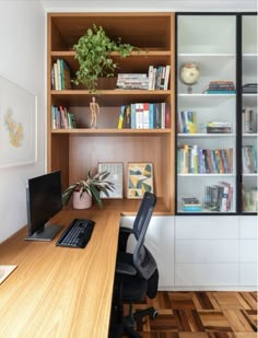 a desk with a laptop computer and bookshelf behind it in front of a window