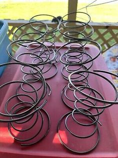 several metal rings sitting on top of a red table next to a blue container and fence