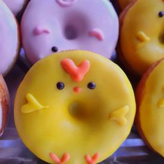 there are many donuts that have faces on them, one is yellow and the other is pink