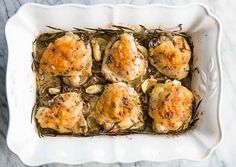 baked chicken in a white casserole dish with herbs