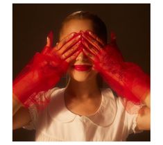 a woman wearing red gloves covering her eyes