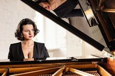 a woman sitting at a piano with her reflection in the mirror