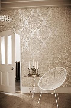 a white chair sitting on top of a hard wood floor next to a wallpaper