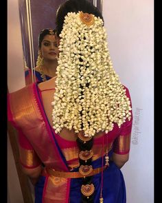 a woman in a blue sari with white flowers on her head and the back of her head