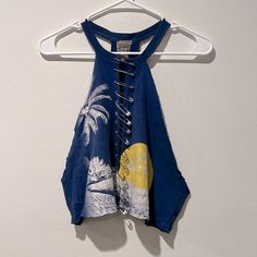 a tank top hanging on a hanger with a palm tree and beach scene print