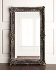 a large ornate mirror sitting on top of a wooden floor next to a white wall