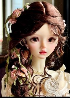 a close up of a doll with long hair and flowers in it's hair