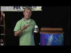 a man standing in front of a fish tank holding a bottle of pet care products