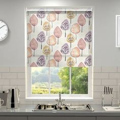 a kitchen with a window covered in colorful trees on the side and a clock mounted to the wall