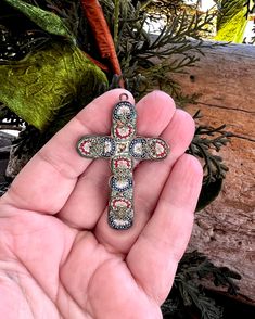 a hand holding a cross ornament in it's palm